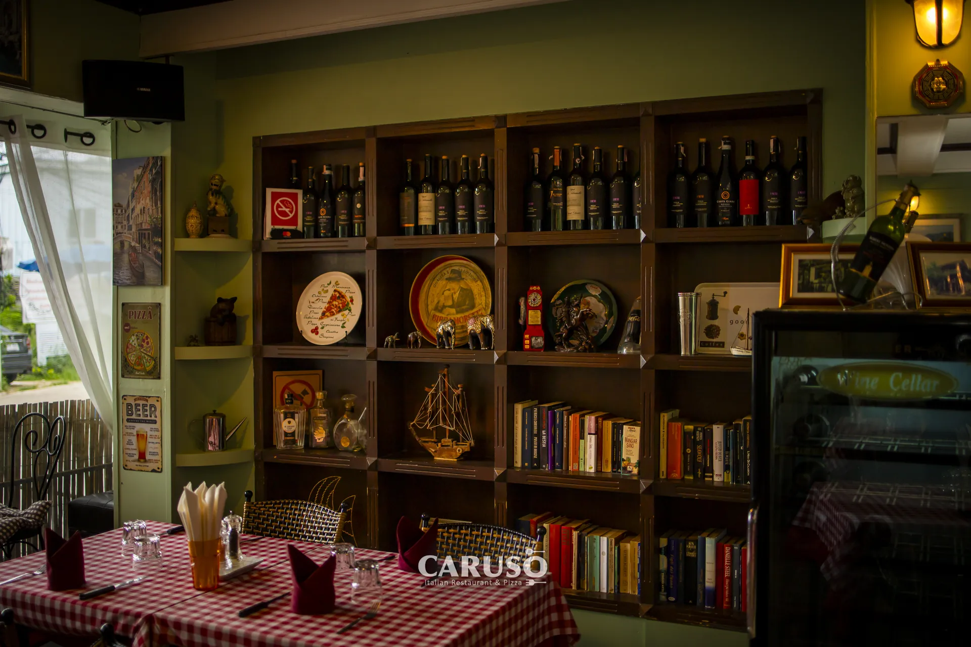 Tables set with red-checked tablecloths beside the wine and book shelves